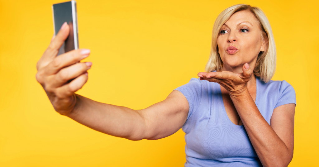 A woman blowing a kiss while on her cellphone.