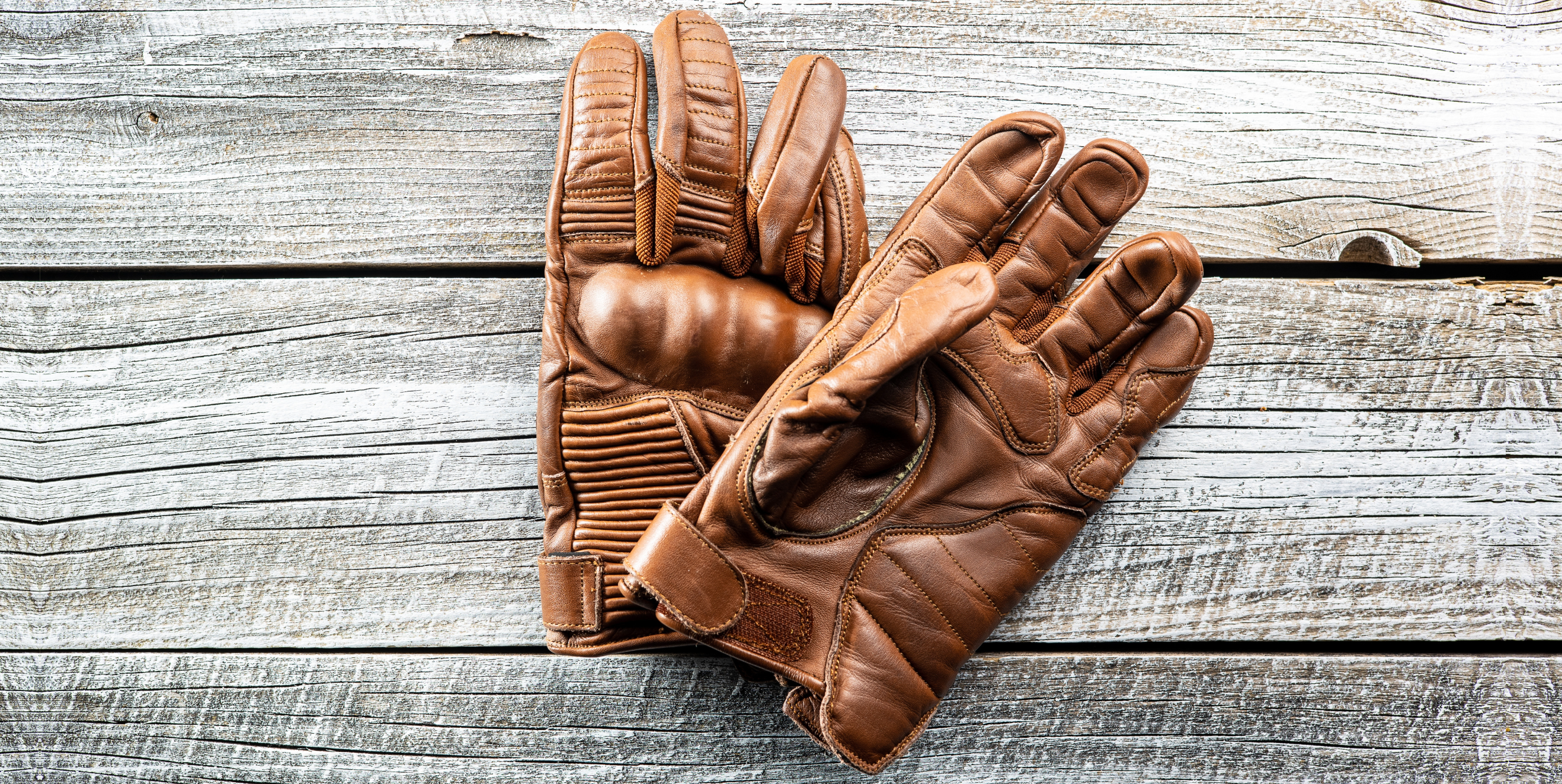 Brown leather gloves on a wooden background