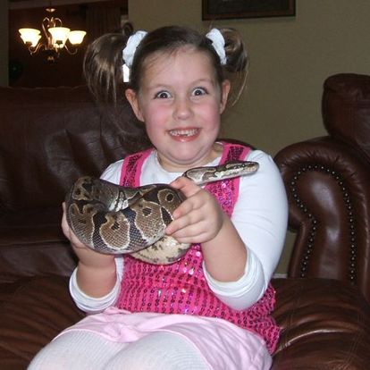 Excited girl holds a ball python.
